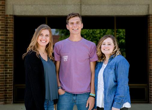three students smiling outside of building